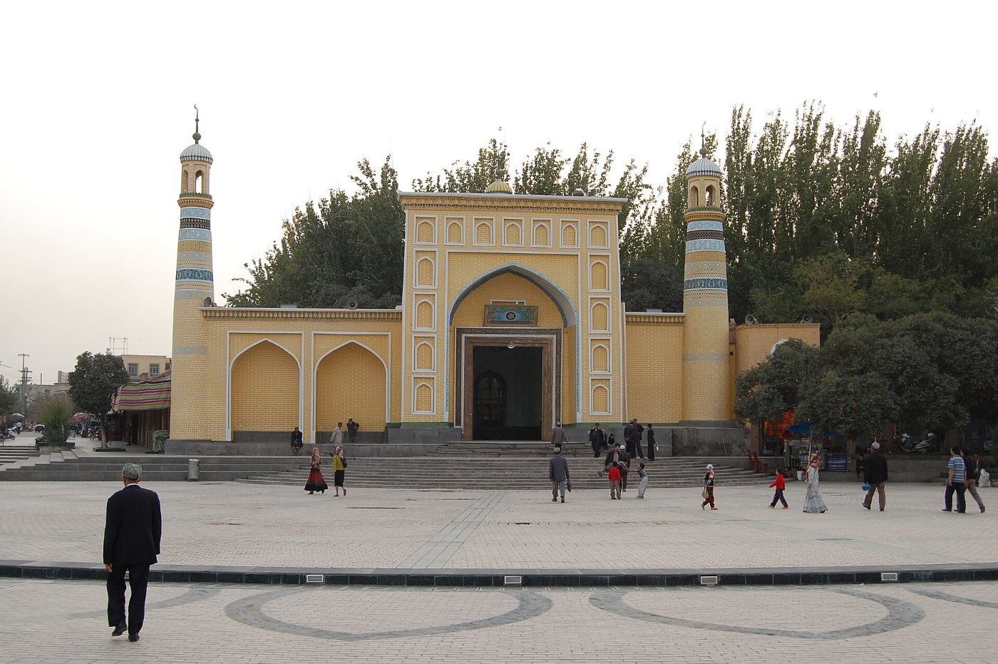 The yellow facade of the Id Kah Mosque in Kashgar with two minarets and a square in front