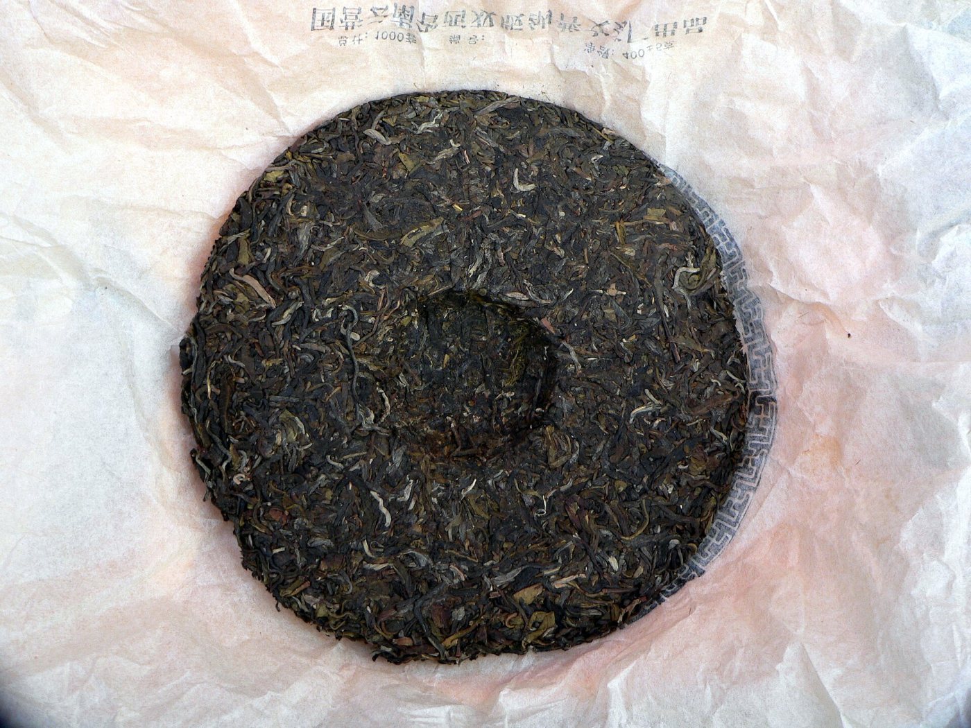 A round pressed cake of pu-erh tea on its unwrapped paper