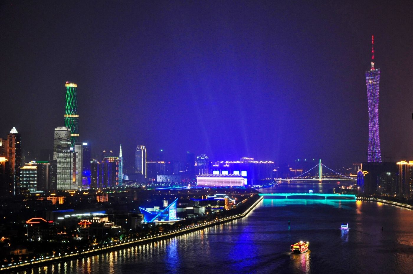Kanton nocą: podświetlona wieża Canton Tower i wieżowce Zhujiang New Town nad Rzeką Perłową, po której płyną statki wycieczkowe