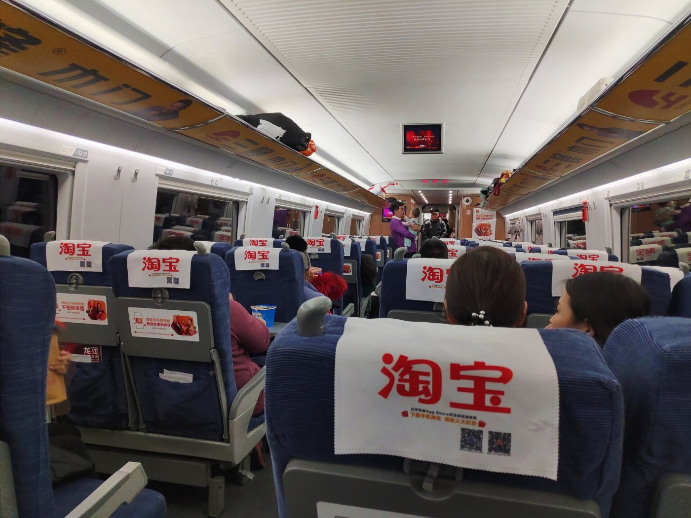 Inside a CRH high-speed train: rows of blue second-class seats and passengers
