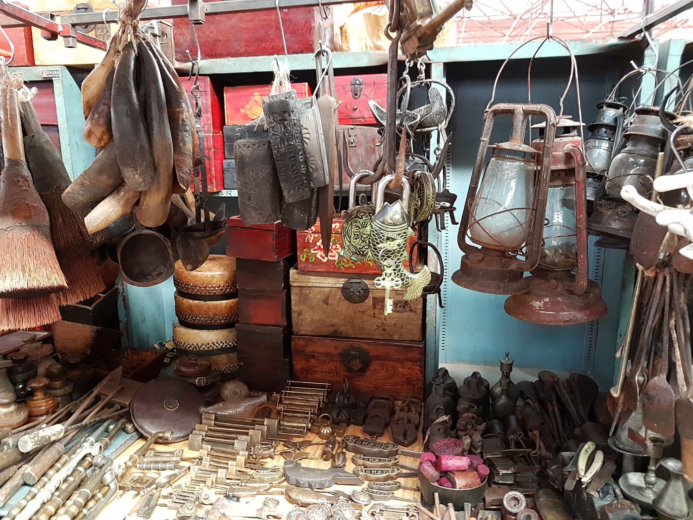 A stall at Panjiayuan market in Beijing: old oil lamps, wooden boxes, brass padlocks and trinkets for sale