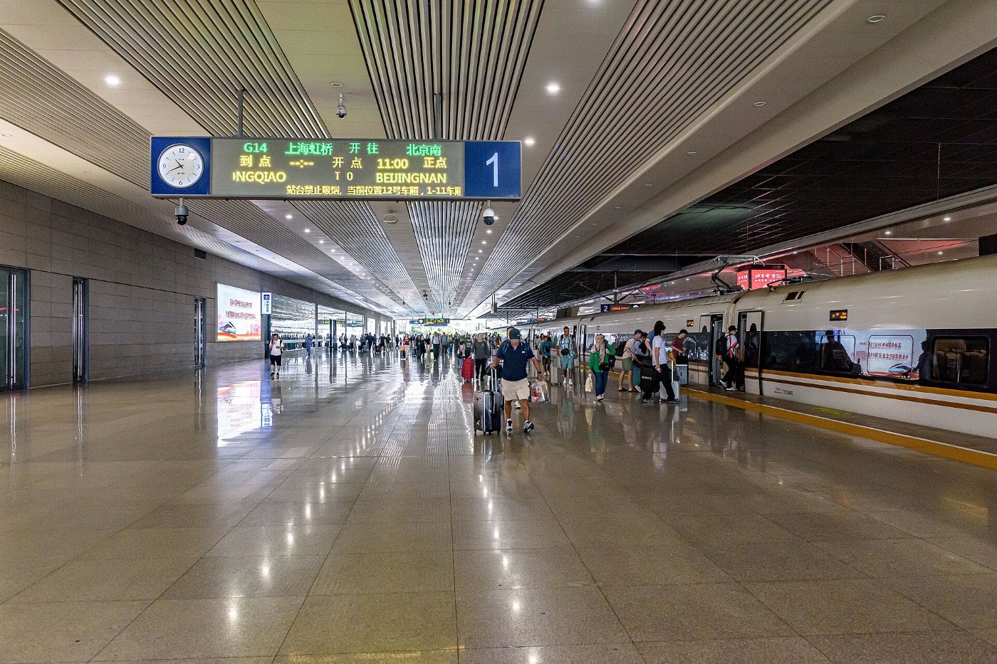 Peron 1 na dworcu Shanghai Hongqiao: szybki pociąg Fuxing przy peronie, podróżni z walizkami i tablica z numerem peronu