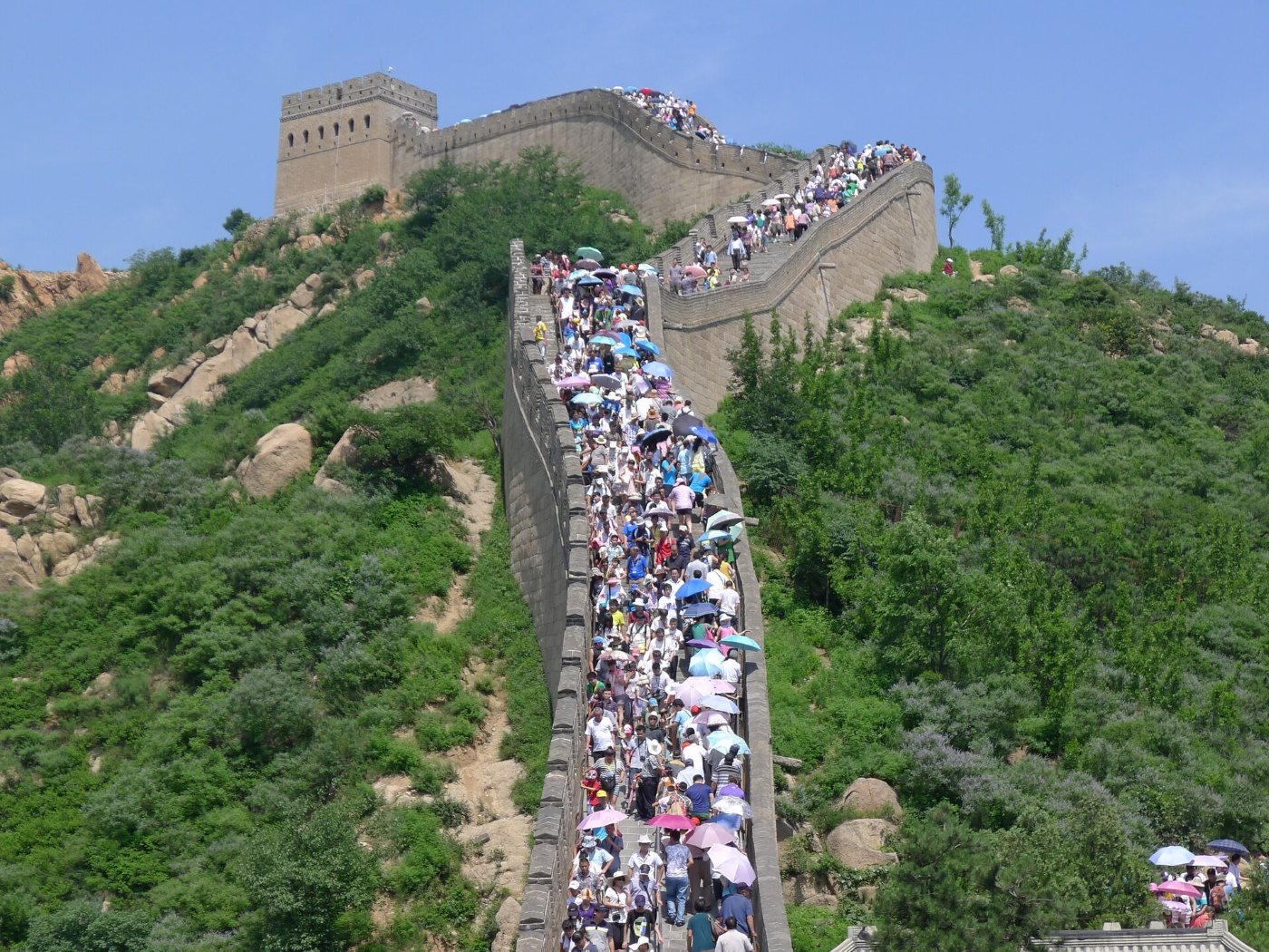 Crowds of tourists with umbrellas on the Great Wall at Badaling, a line of people up to the watchtower on the summit