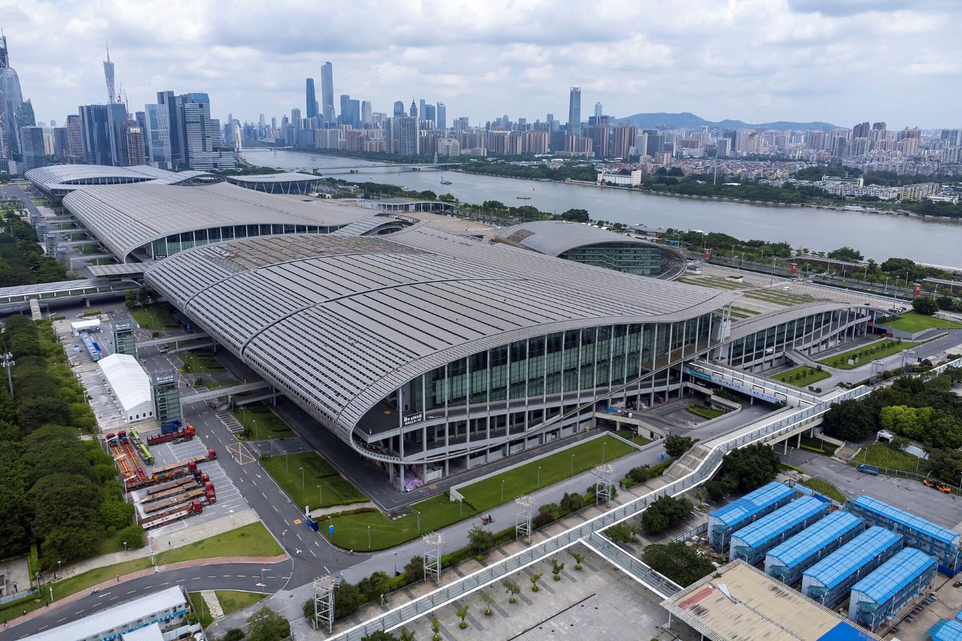 Aerial view of Zone B of the Canton Fair Complex: a huge arched roof by the Pearl River, with the skyscrapers of Zhujiang New Town behind