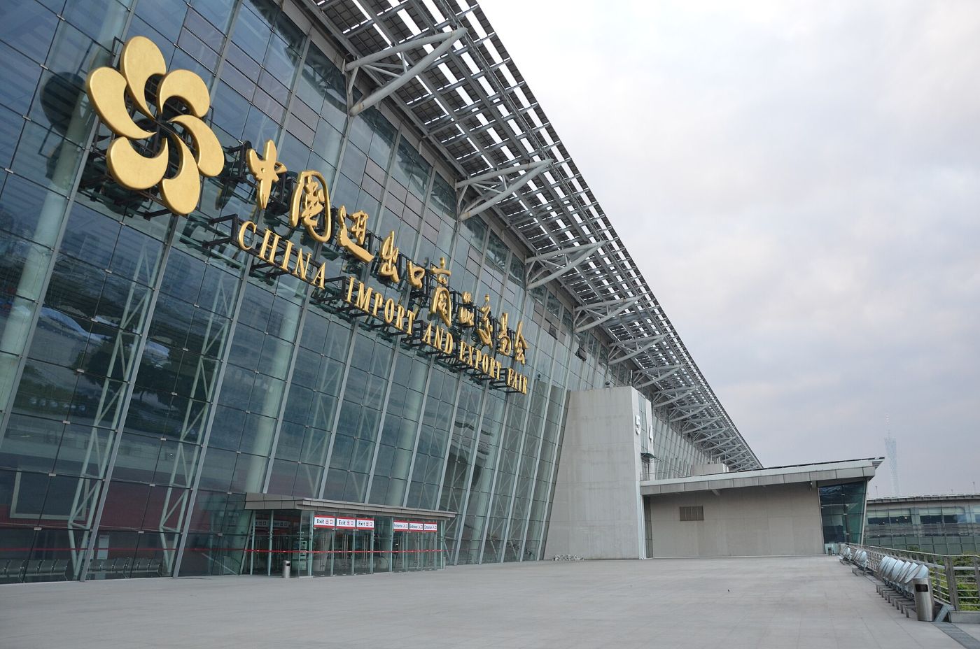 The entrance to the Canton Fair Complex: a glass facade with a gold flower-shaped logo and the words China Import and Export Fair