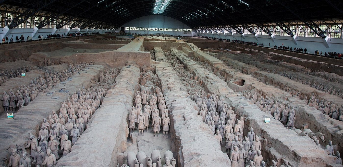 Pit 1 of the Terracotta Army in Xi'an: rows of clay soldiers standing in earthen corridors under a huge hall, visitors around the edge