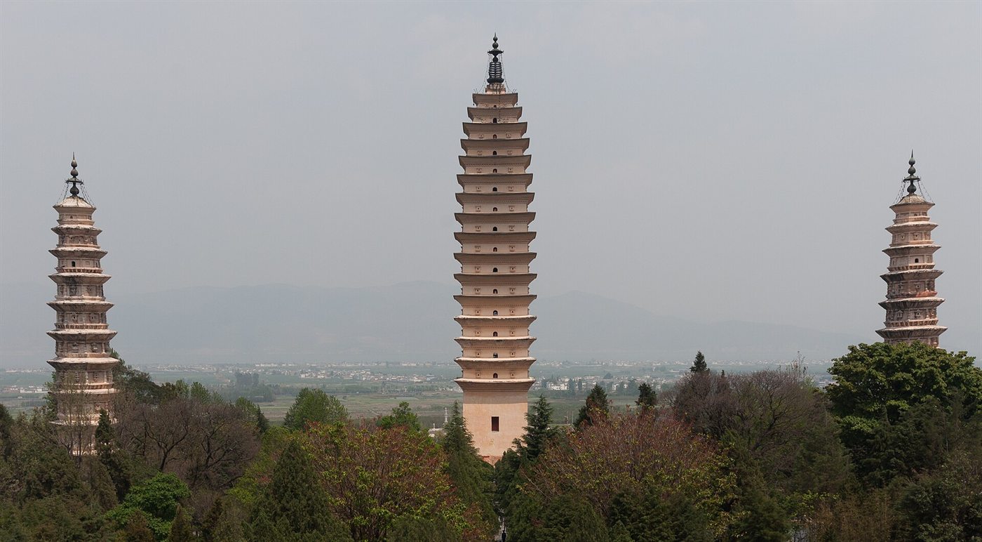 The three white pagodas of Chongsheng Temple in Dali – a tall one in the middle and two smaller ones on either side – above green trees, with the Erhai valley behind